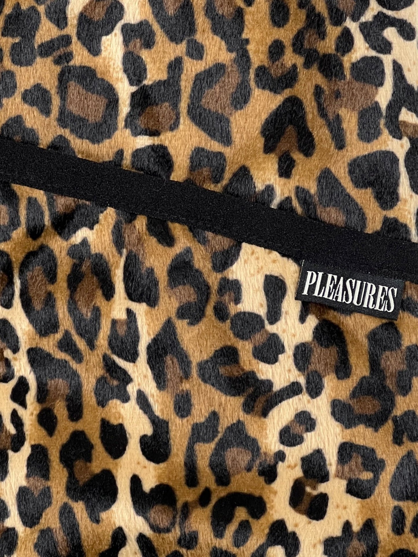 A close up of a PLEASURES cheetah print polyester scarf.