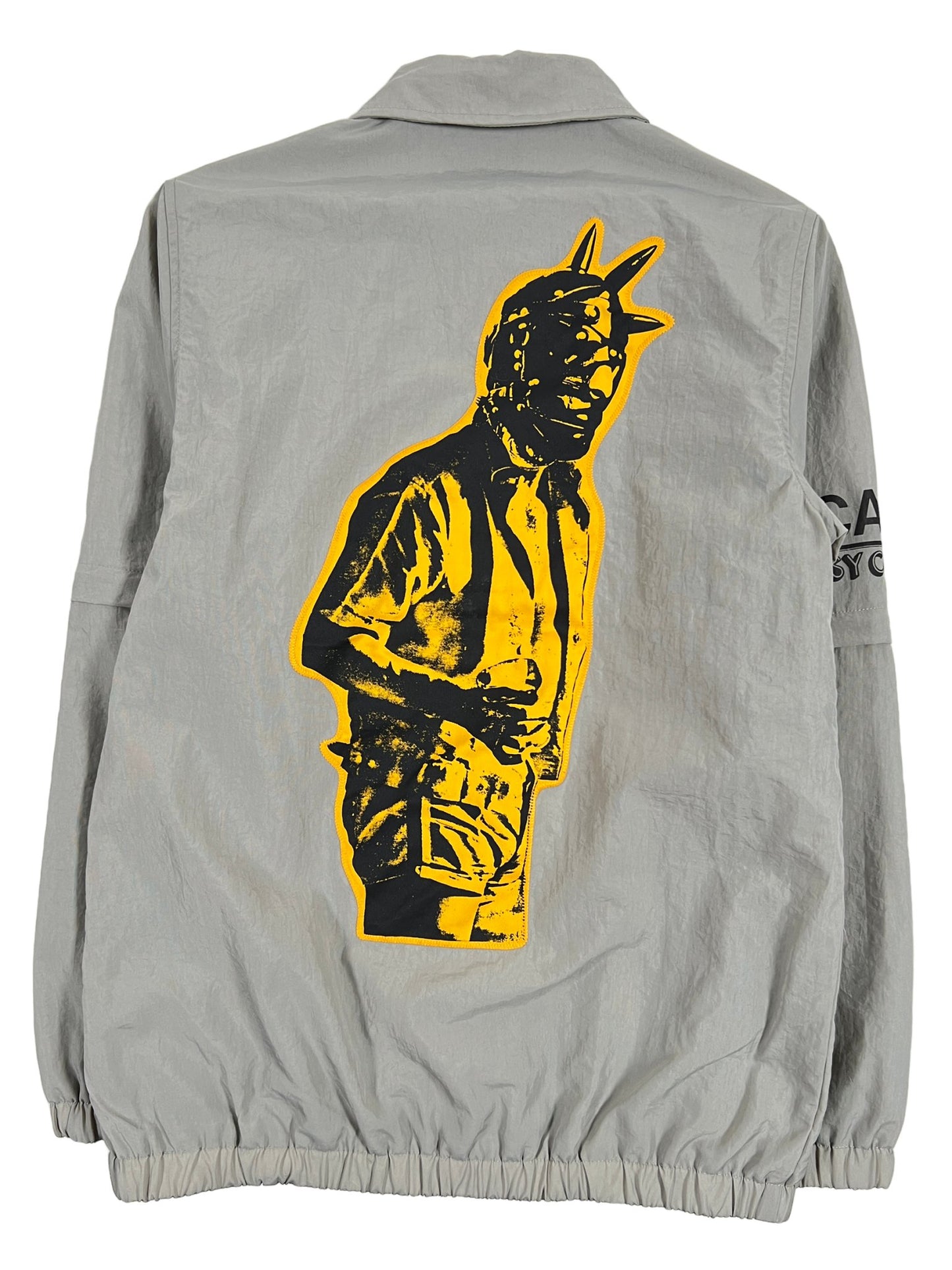 A grey PLEASURES Polyester jacket with an embroidered logo detail of a man holding a gun.