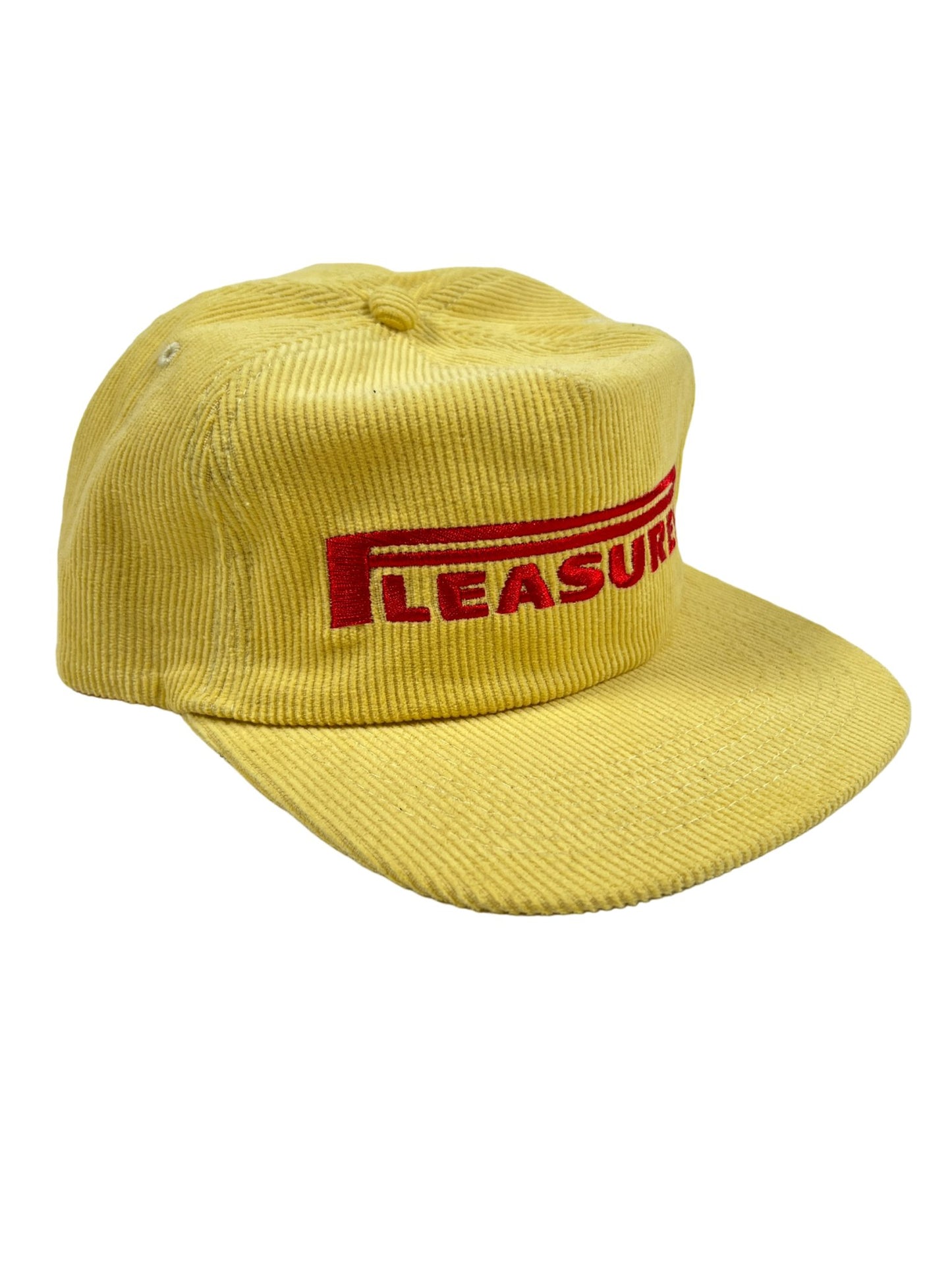 A yellow PLEASURES snapback hat with the word "leisure" embroidered on it.