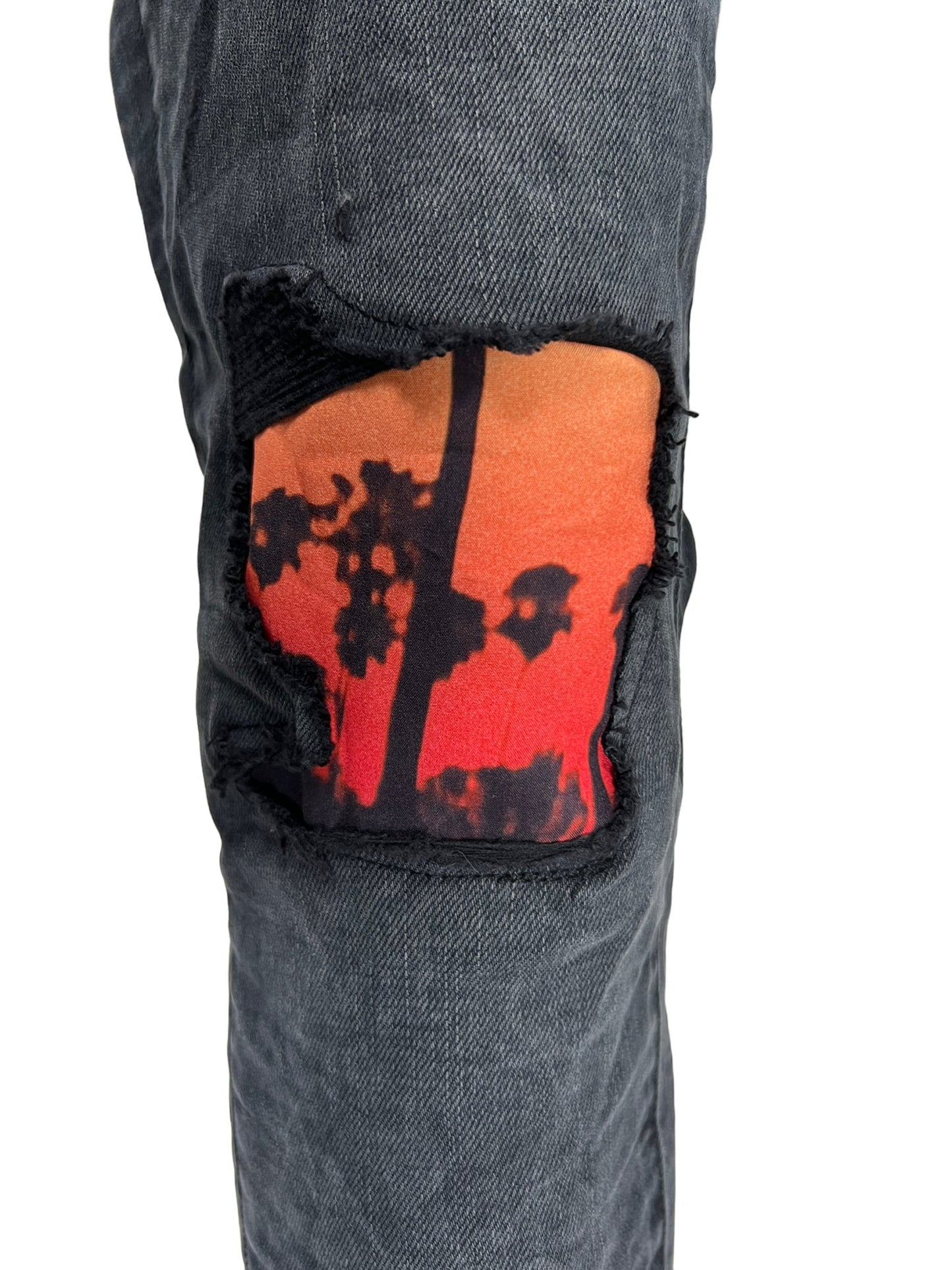 A pair of PURPLE BRAND ripped jeans with an image of a palm tree.
