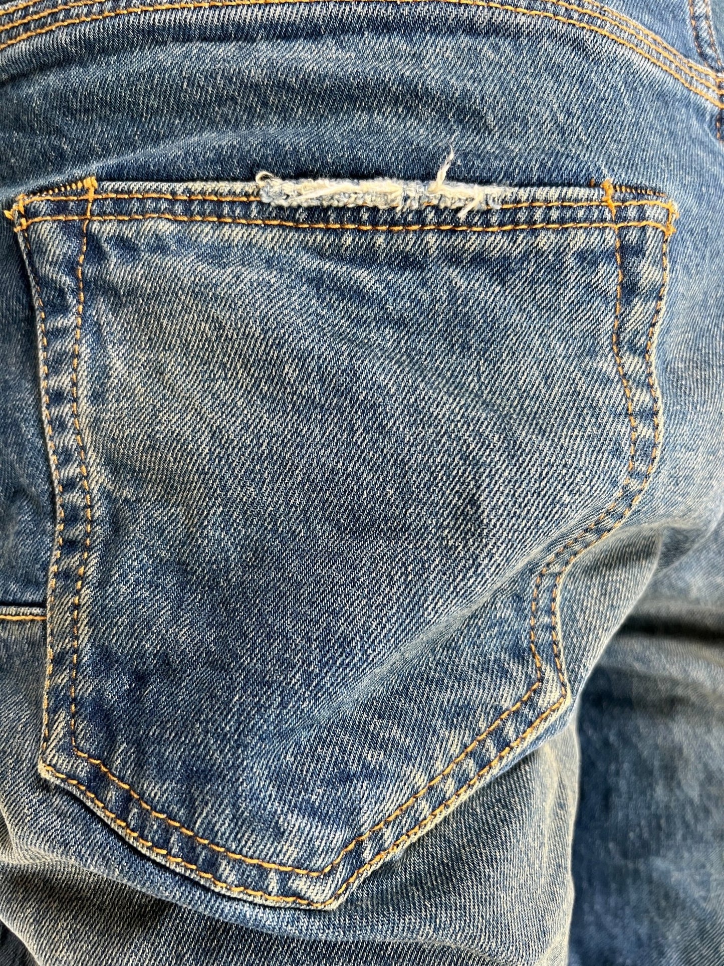 A pair of PURPLE BRAND P001-DPMI DIRTY PATINA DK INDIGO jeans with a hole in the pocket.