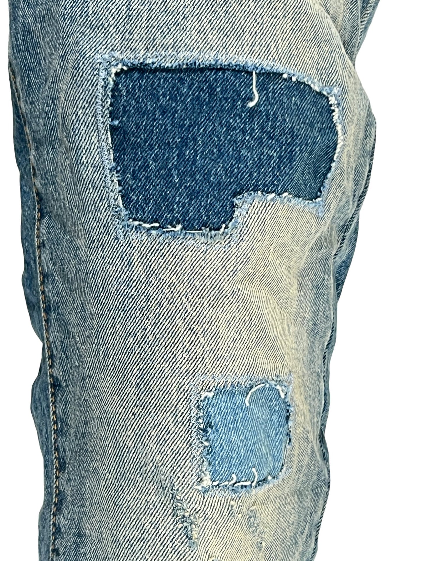 A pair of Purple Brand P004-PRFL Patch Repair Flare Mid Indigo jeans with holes in them.