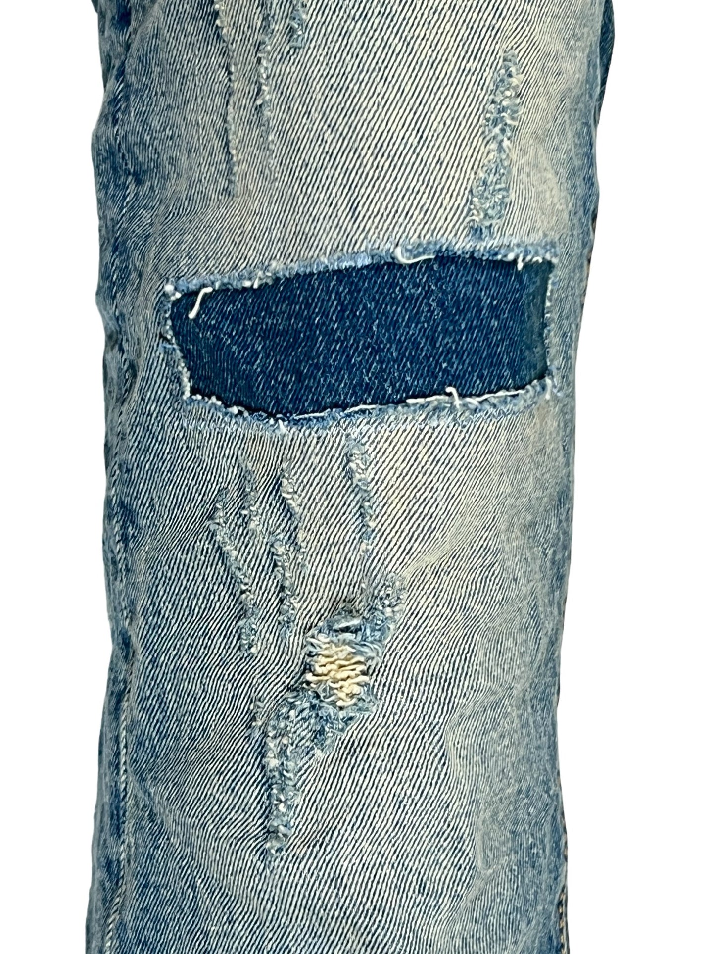 A pair of PURPLE BRAND P004-PRFL PATCH REPAIR FLARE MID INDIGO jeans with holes in them.