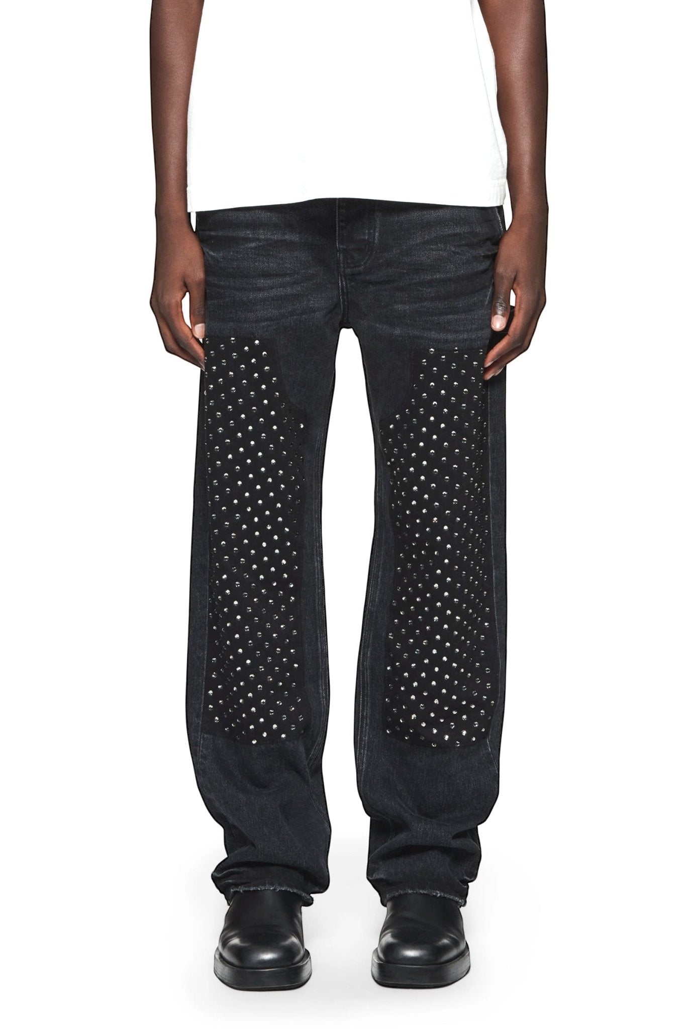 A man wearing a white t-shirt and PURPLE BRAND JEANS P015-CCBL CRYSTAL CARPENTER BLACK stretch denim jeans.
