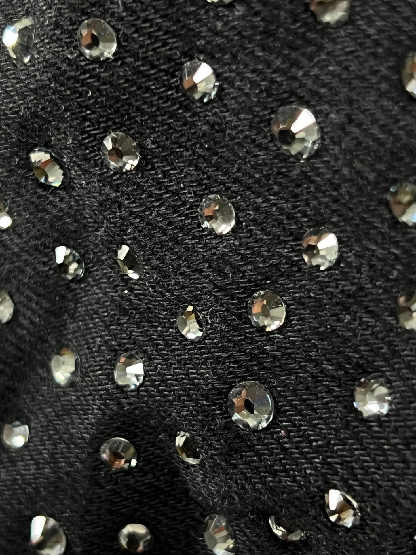 A close up of a PURPLE BRAND JEANS P015-CCBL CRYSTAL CARPENTER BLACK stretch denim fabric with crystal-studded rhinestones on it.