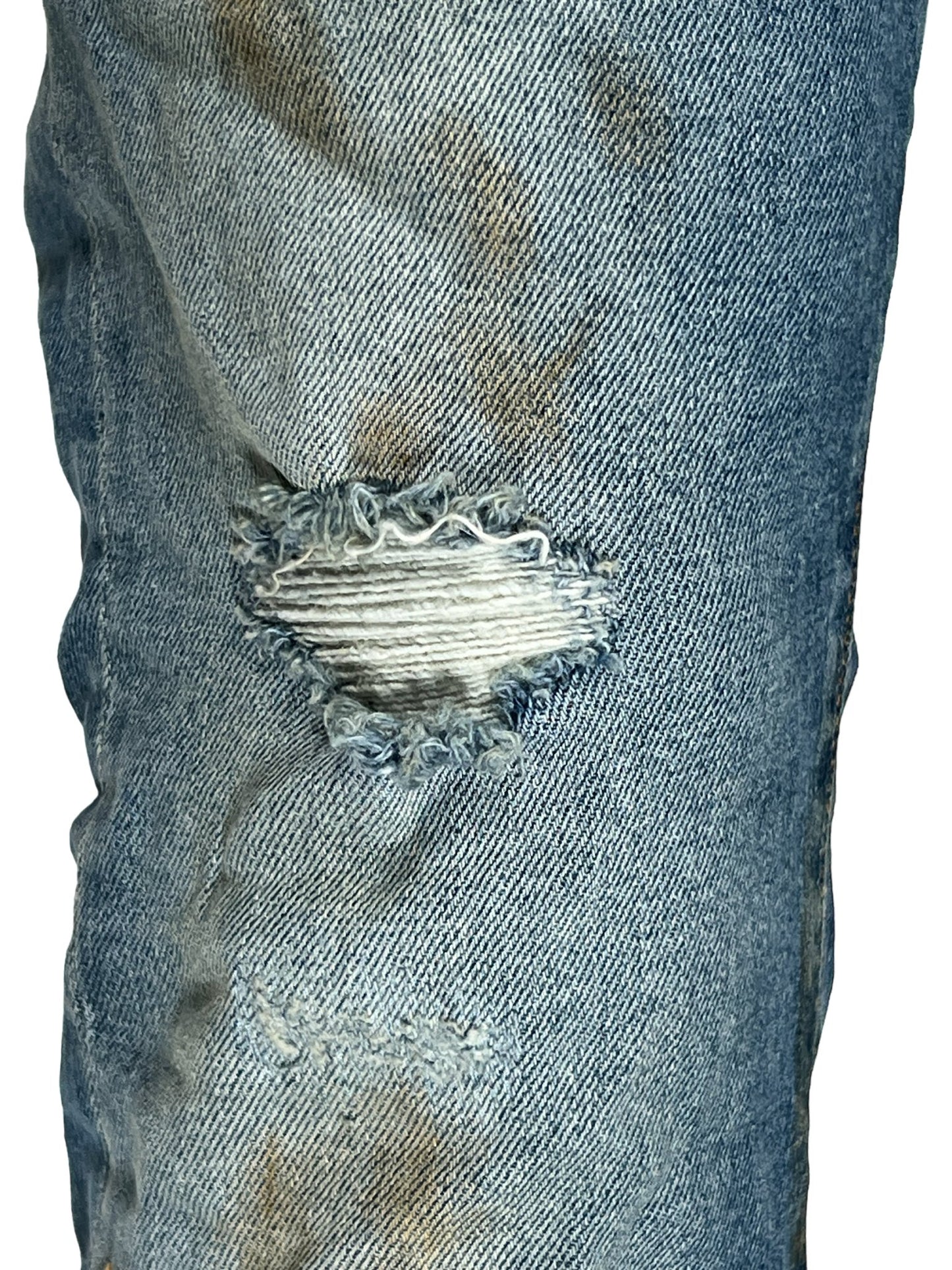 A close up of a pair of PURPLE BRAND JEANS P001-FLIP FADED LIGHT INDIGO PAINTER with holes in them from Purple Brand.