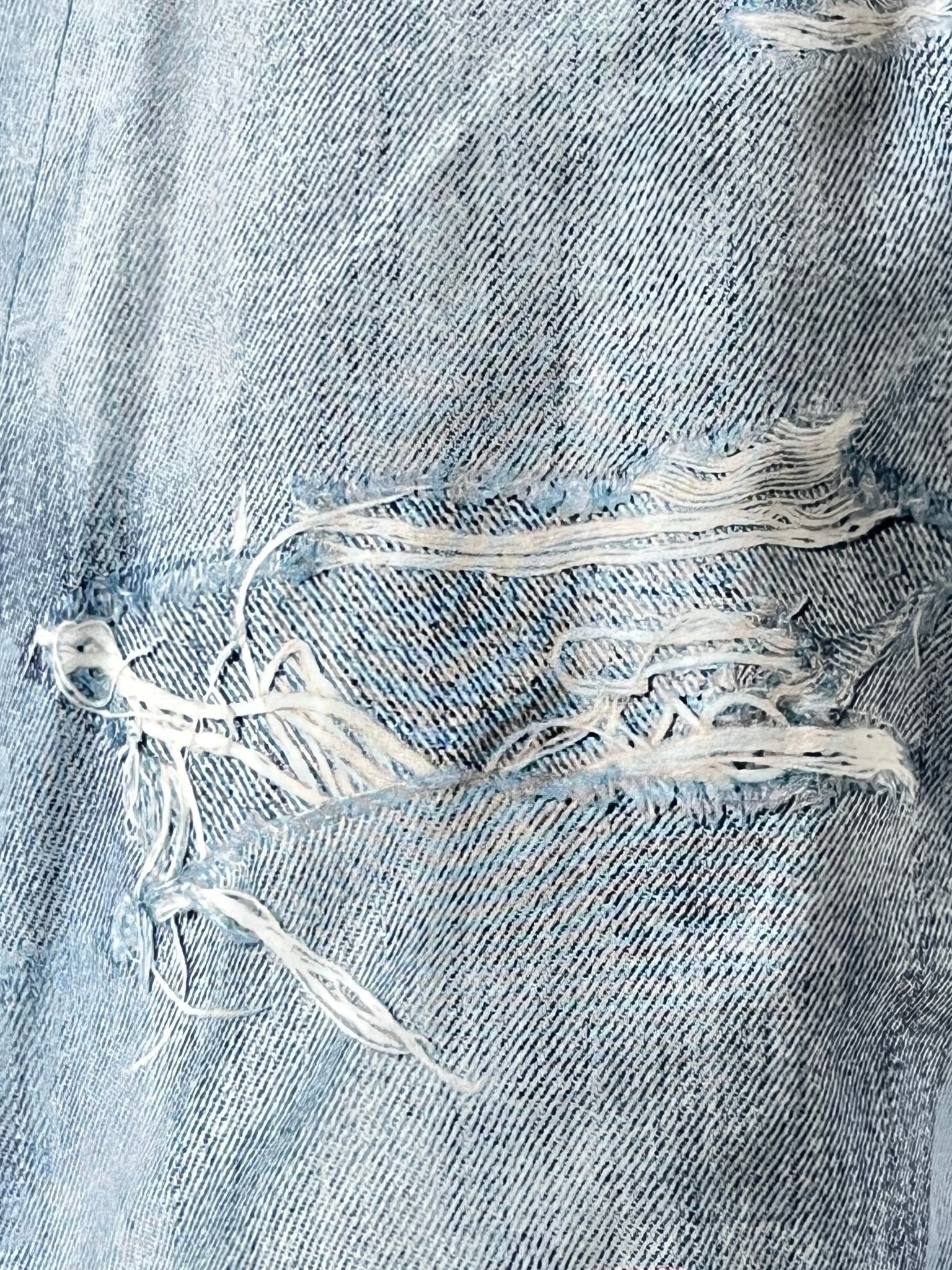 Close-up of the Purple Brand P504-PIDD All Round Short Water Print in Light Indigo, highlighting its rustic charm with visible frayed and torn sections.