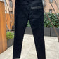 A pair of RH45 premium denim jeans hanging outdoors against a backdrop of trees and a building.