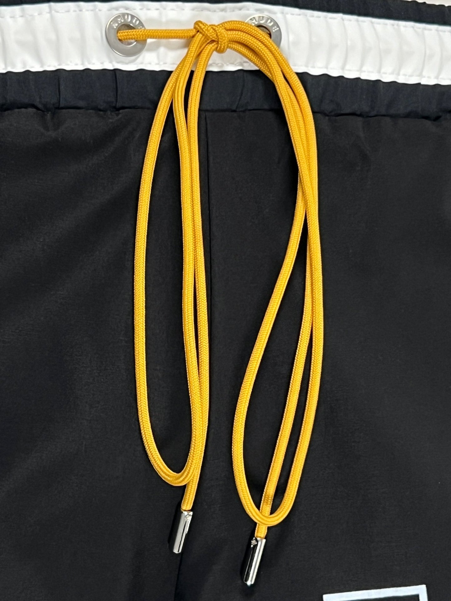 RHUDE BASKETBALL SWIM SHORT BLK with a white waistband and a yellow drawstring.