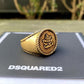 A metallic gold DSQUARED2 RIM0019 ring on top of a box.