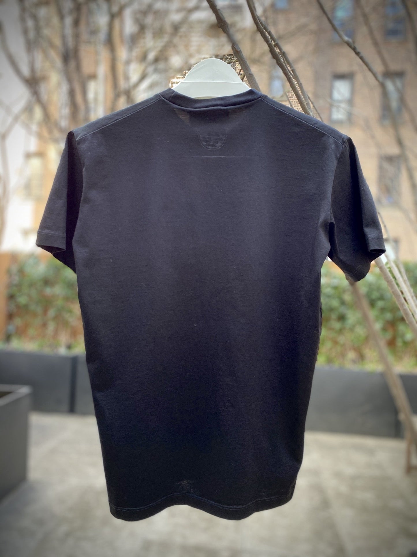 A black DSQUARED2 S71GD1021 t-shirt hanging on a tree.